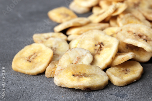sweet banana slices on grey background, top view with space for text. Dried fruit as healthy snack