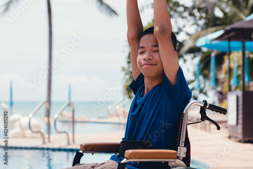 Asian special child on wheelchair is smile, playing and exercise activity on sea beach and pool at summer, Lifestyle of disability child in the education age, Happy disabled kid in travel concept.