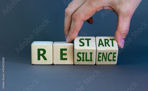 Restart and resilience symbol. Businessman turns cubes and changes the word 'restart' to 'resilience'. Beautiful grey background. Business and restart - resilience concept. Copy space.