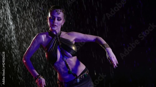 contemporary belly dancer lady is dancing under rain at night, woman is moving erotically