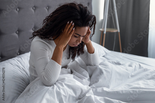 Black woman suffering from headache or migraine in bed photo