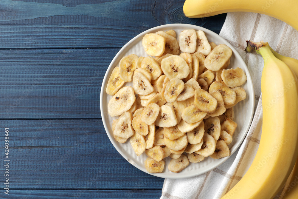Composition with sweet dried banana slices, fresh bananas on a blue wooden background. Dried fruit as healthy snack Composition with sweet dried banana slices, fresh bananas on a blue wooden background. Dried fruit as healthy snack