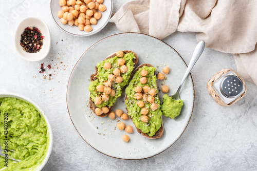 Mashed avocado and chickpeas on toasted bread. Healthy vegan toasts top view