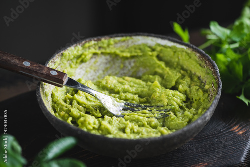 Mashed avocado sauce in a bowl on dark background. Healthy vegan avocado sauce