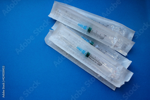 Syringes with a needle in the package lie on a blue background. Vaccination. The concept of medicine and immunity. Vaccination against viral infections. Copy space. Flatly