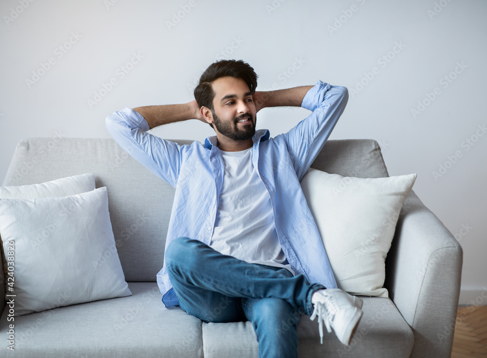 Relaxed Arab Guy Leaning Back On Couch With Hands Behind Head