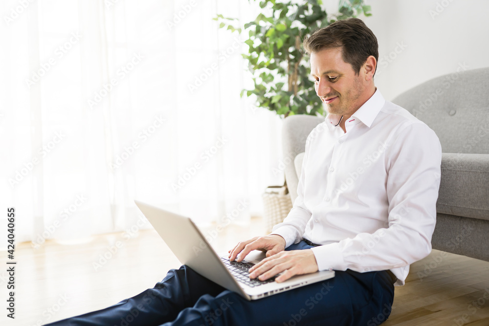 Happy smiling young man watching and working on computer laptop at home Happy smiling young man watching and working on computer laptop at home
