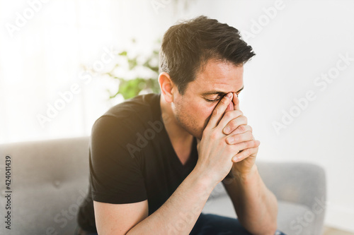 Depressed man thinking at home on couch