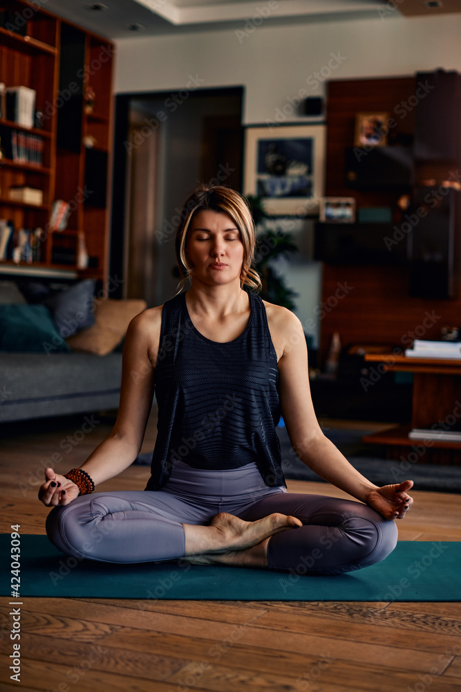 Φωτογραφία A middle-aged woman sitting in a lotus yoga pose and meditating with eyes closed