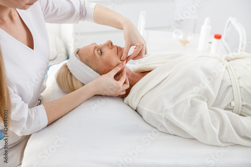 Bilde på lerret Senior female is lying on back, getting face lifting massage