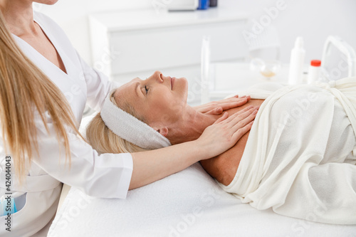Senior female is lying on back, getting face lifting massage. Facial massage beauty treatment. Wellness, beauty and relaxation concept