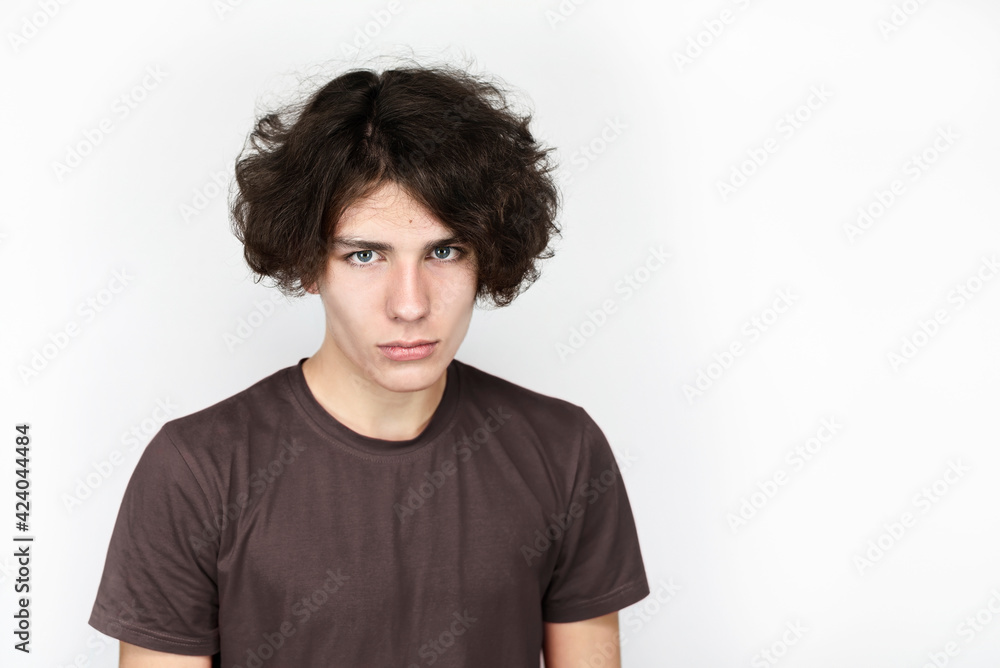 Portrait of a teenage boy with a beautiful face, long dark hair. A teenager with sadness on his face regrets that his childhood ended so soon and he needs to grow up Portrait of a teenage boy with a beautiful face, long dark hair. A teenager with sadness on his face regrets that his childhood ended so soon and he needs to grow up