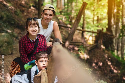 A young teen girl and her two brothers, a senior and a junior, are resting together in the mountains in summer. Here in nature, they rest from modern technology, gadgets and breathe fresh air
