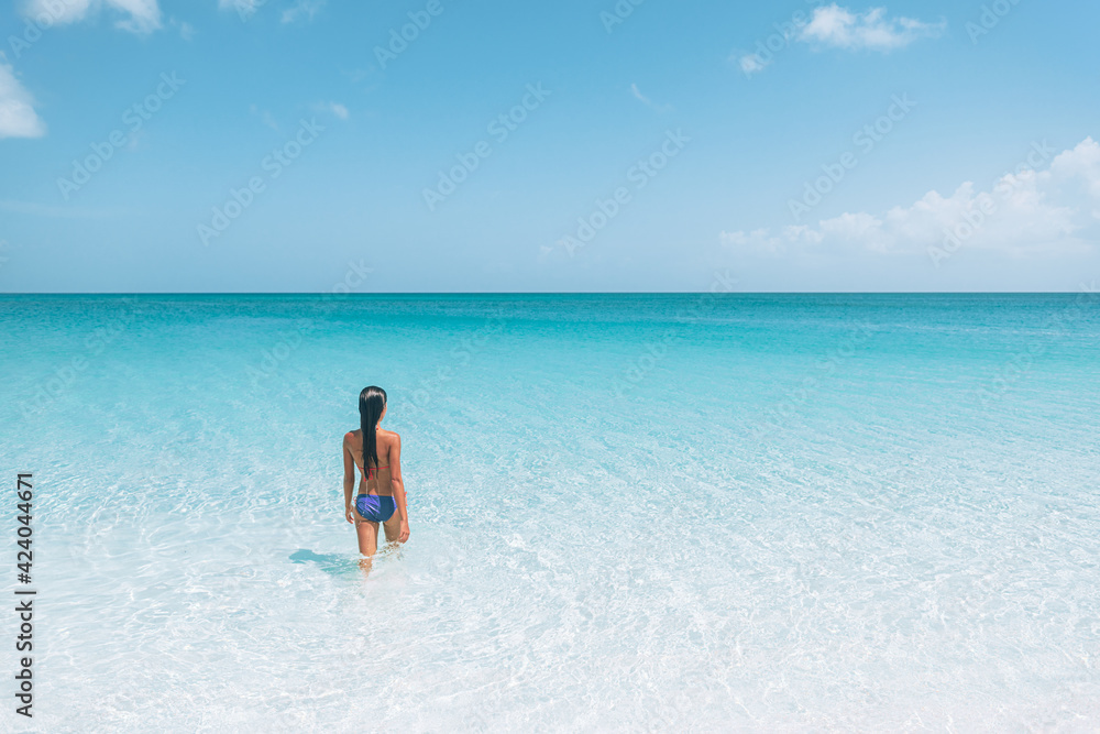Beach travel Caribbean vacation. Bikini woman relaxing sunbathing in water tanning enjoying sun. Winter holidays.
