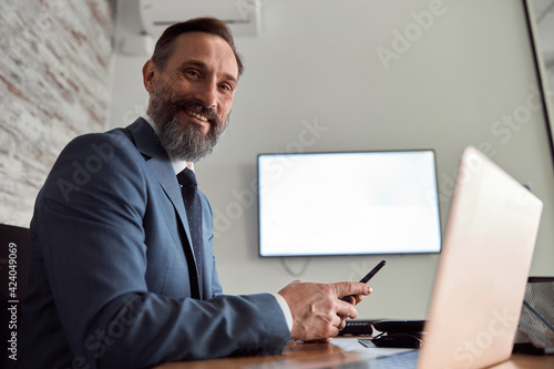 Happy adult caucasian man is working in a modern office