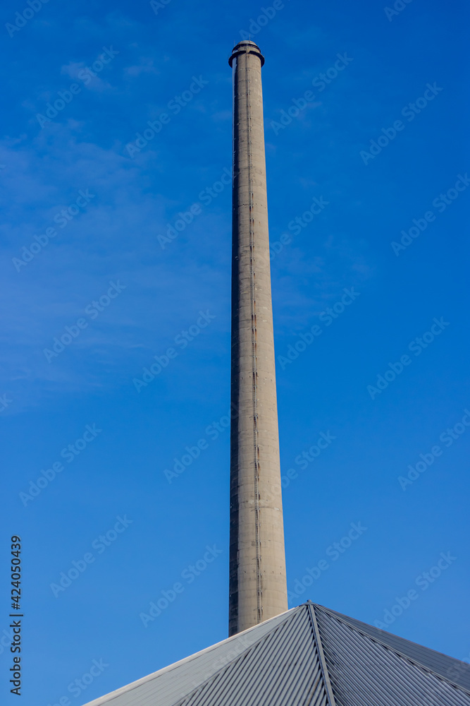 Huge chimney of an old disused and abandoned cement factory, sunny day with a blue sky in South Limburg, the Netherlands