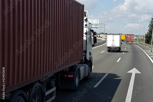 Camión contenedor junta a una flecha en el asfalto que le indica la dirección circulando por la autopista en dirección al puerto. photo