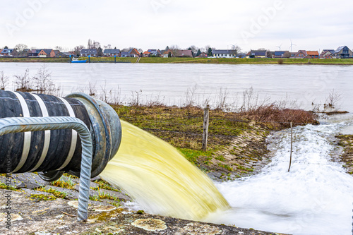 Water flowing into the river Meuse from a pipe of a water pump, system to control high levels of streams and prevent flooding in Geulle aan de Maas in South Limburg, the Netherlands