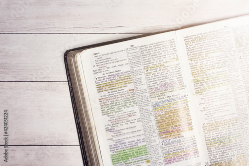Used and Highlighted Bible Open on a White Wood Table