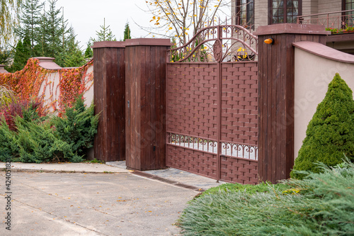 metal front gates with elements of forged parts with stone pillars, fencing of private territory