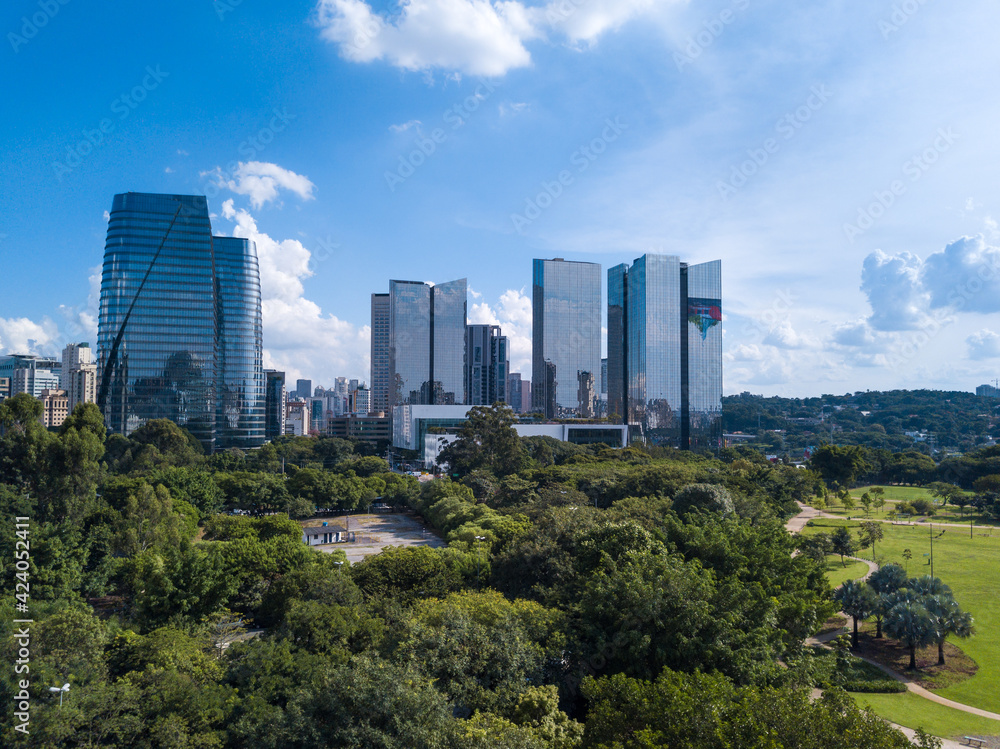 Beautiful aerial view of modern architectural glass corporate buildings, trees of Parque do Povo park and São Paulo city skyline in sunny summer day. Concept of urban, cityscape, metropolis. Brazil.