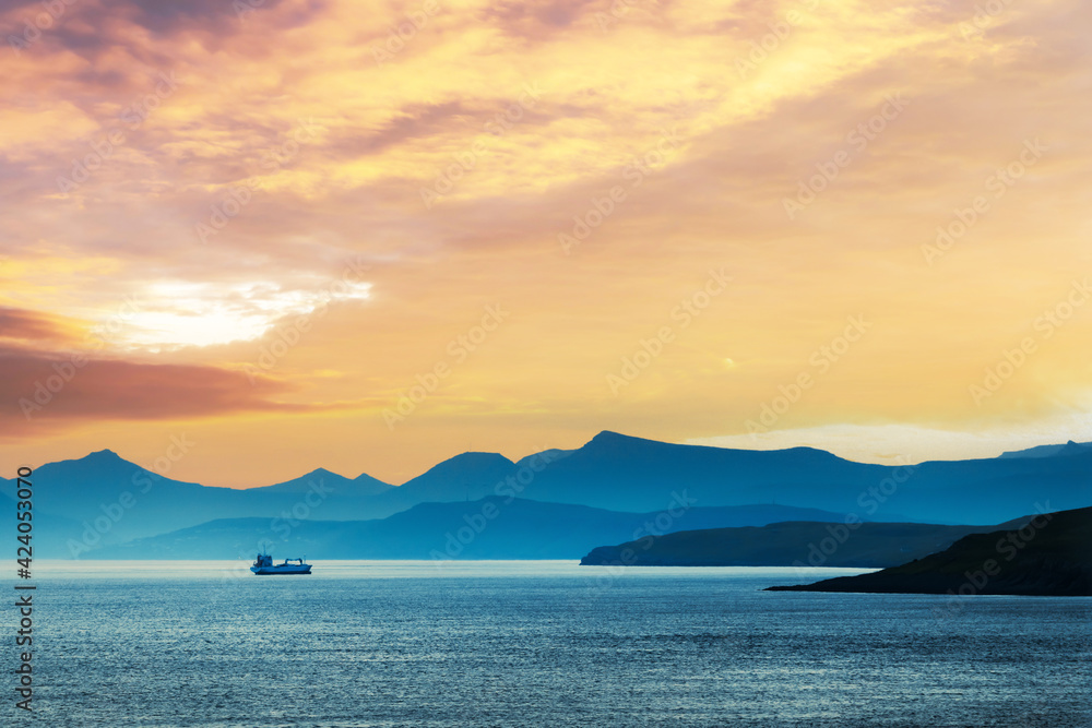 Beautiful summer sunset on Faroe Islands, Denmark. Lonely ship in the coastal waters. Landscape photography