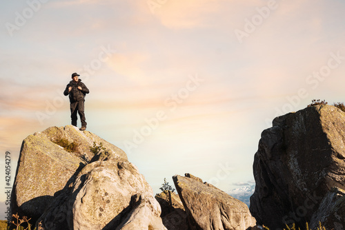 hiker man climbed on a rock in the mountain watching the sunset. mountain sports and activities. trekking. weekend getaway.