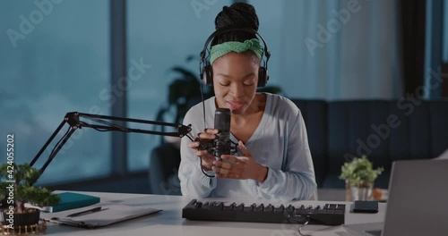 African attractive inspired woman music artist recording audiotrack, singing song and using electronic piano synthesizer keyboard in living room. photo