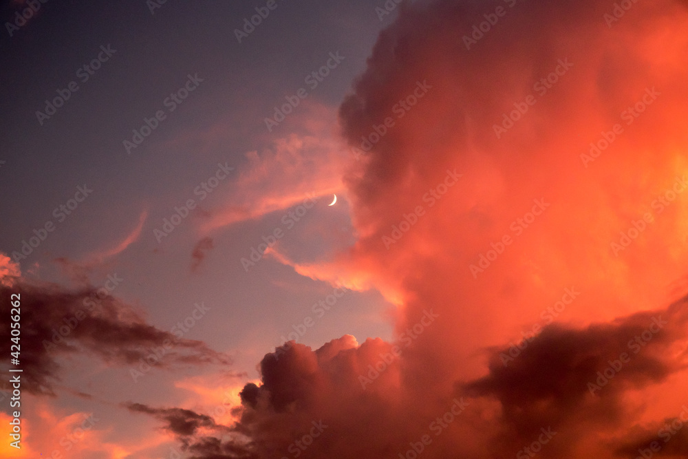 Crescent moon through a bright orange cloudbank