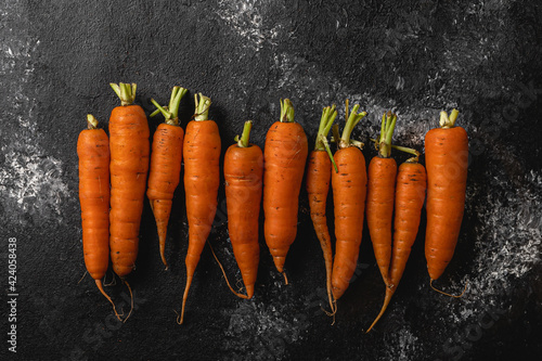 display of arranged group of organic carrots on dark background