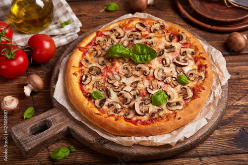 Pizza with mushrooms. American style homemade pizza with champignon mushrooms, mozzarella cheese and tomato sauce. Freshly baked and served with basil leafs. Vegetarian dish