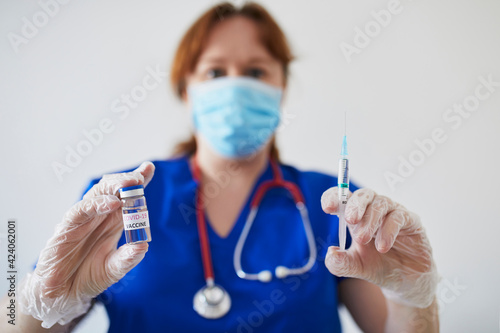 Female doctor or nurse holding syringe and COVID-19 vaccine
