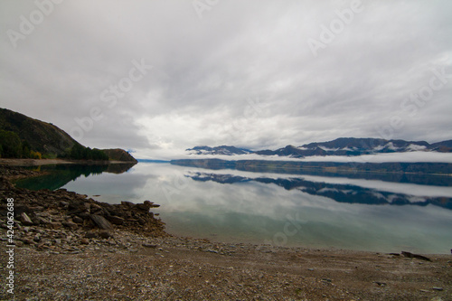 Lake Hawea, South Island of New Zealand. Pristine see- trough blue water reflecting the clouds and mountain mist