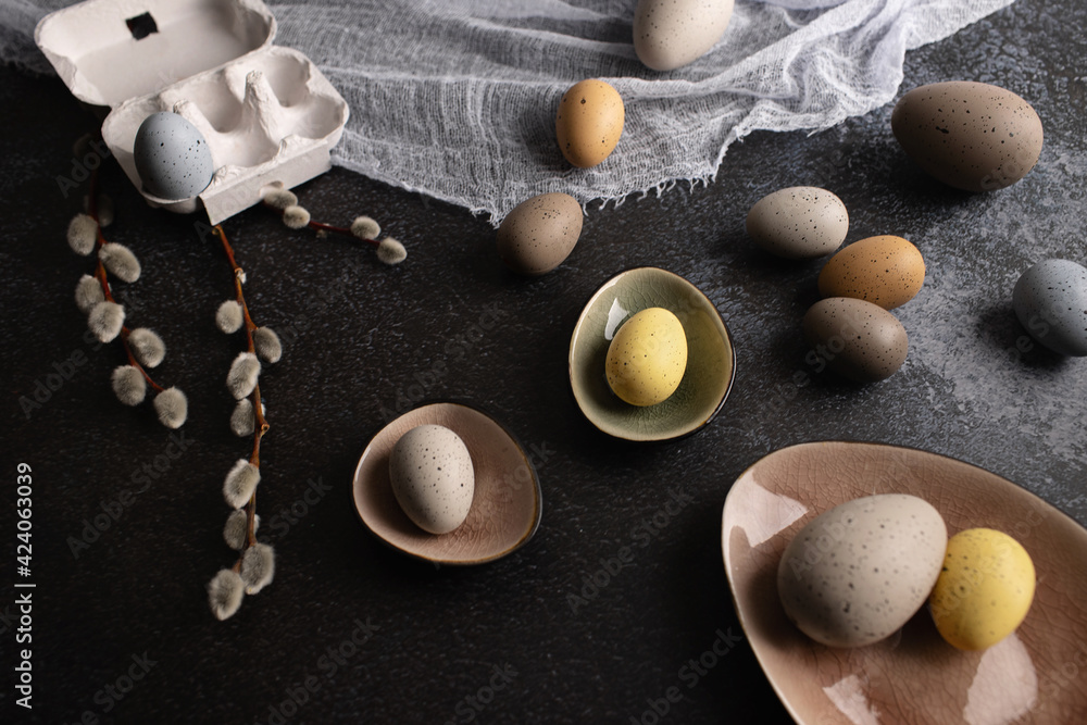 Colourful pastel easter eggs in the nest on a dark background with rustic kitchen decor Colourful pastel easter eggs in the nest on a dark background with rustic kitchen decor