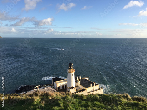 A fishing boat passing in front of the Douglas Head Lighthouse - a lighthouse at Douglas Head on the Isle of Man located between England and Ireland