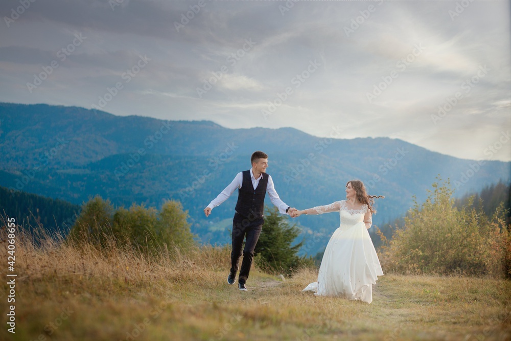 Happy gorgeous bride and stylish groom run and having fun, wedding couple, luxury ceremony at mountains with amazing view