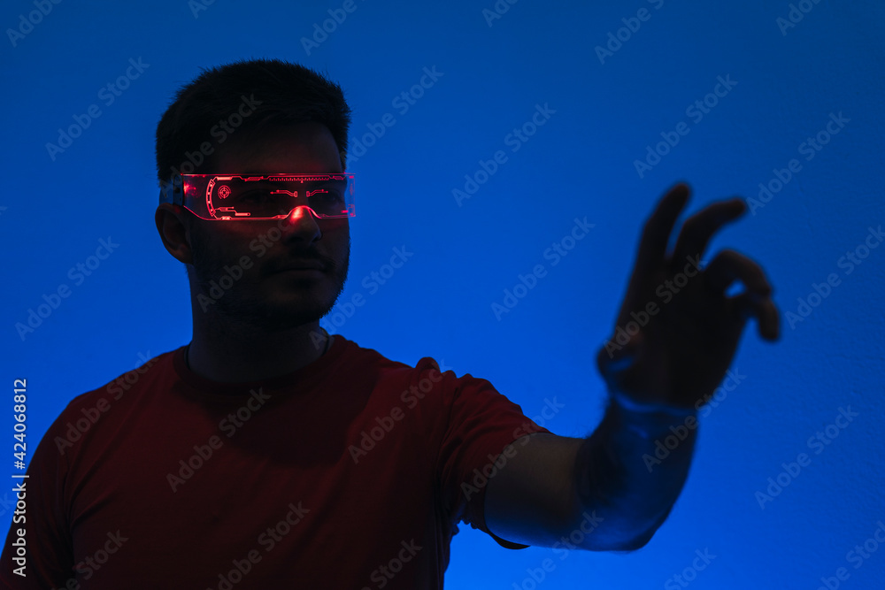 Silueta de un chico con gafas futuristas de luz led en fondo azul. Silueta de un chico con gafas futuristas de luz led en fondo azul.