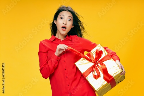 woman of asian appearance with a gift in hands holiday emotions christmas yellow background