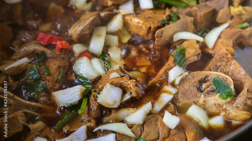 Fototapeta premium Pork chops in a boiling stewed with parsley, onion and readseasoning pepper
