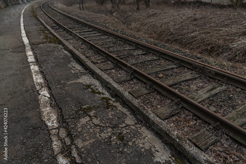 Old, dilapidated and abandoned railway station with rusty railway tracks and wooden railway sleepers