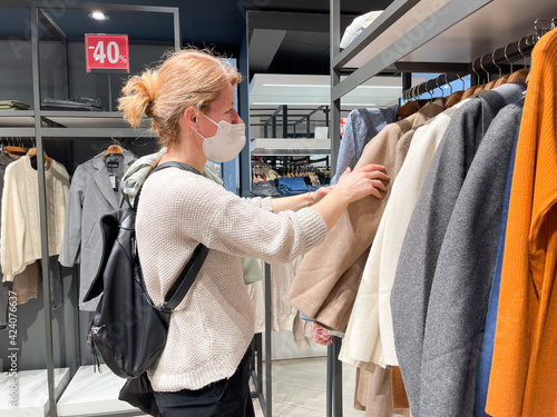  female with protective face mask shopping in a clothing store.