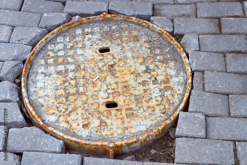 Close-up of a manhole cover, a gray gravel hydrant for the construction industry. Rusty hatch on the street. Road repair concept