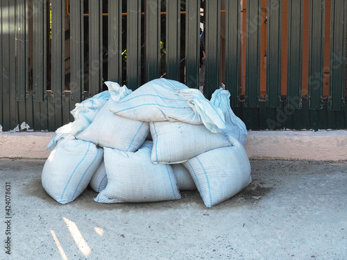 Принти на полотні White sandbags piled up lie on the street near the fence