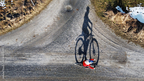 Luftaufnahme mit einer Drohne von einer Fahrradfahrerin auf einer Straße mit Schatten photo