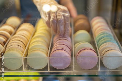 Many colorful macaron eclair in glass showcase at candy shop close up cake cookie assortiment