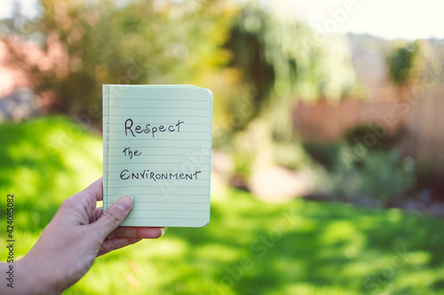 sustainable development, hand holding Respect the Environment message under the sun with garden bokeh bakcground photo