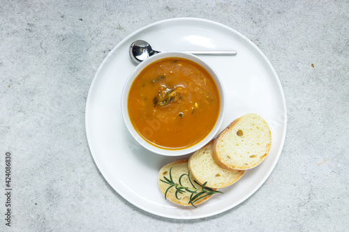 sup labu or pumpkin soup serving with slice of baguette