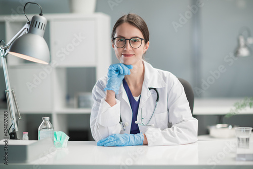 Portrait of a medical specialist in the workplace. A female doctor in medical gloves in the office of a private clinic.