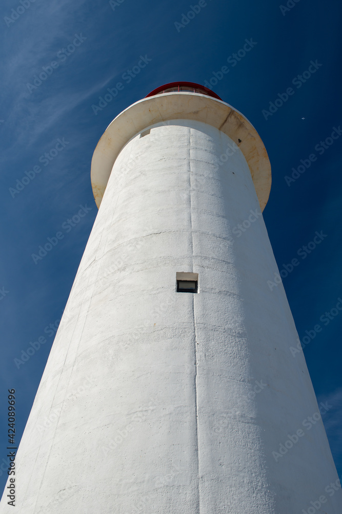 The watch room of a lighthouse.The lantern room has a large green bulb. The building is white with a red rail around the gallery deck.The background is cloudy and there's vignetting around the edges. The watch room of a lighthouse.The lantern room has a large green bulb. The building is white with a red rail around the gallery deck.The background is cloudy and there's vignetting around the edges.