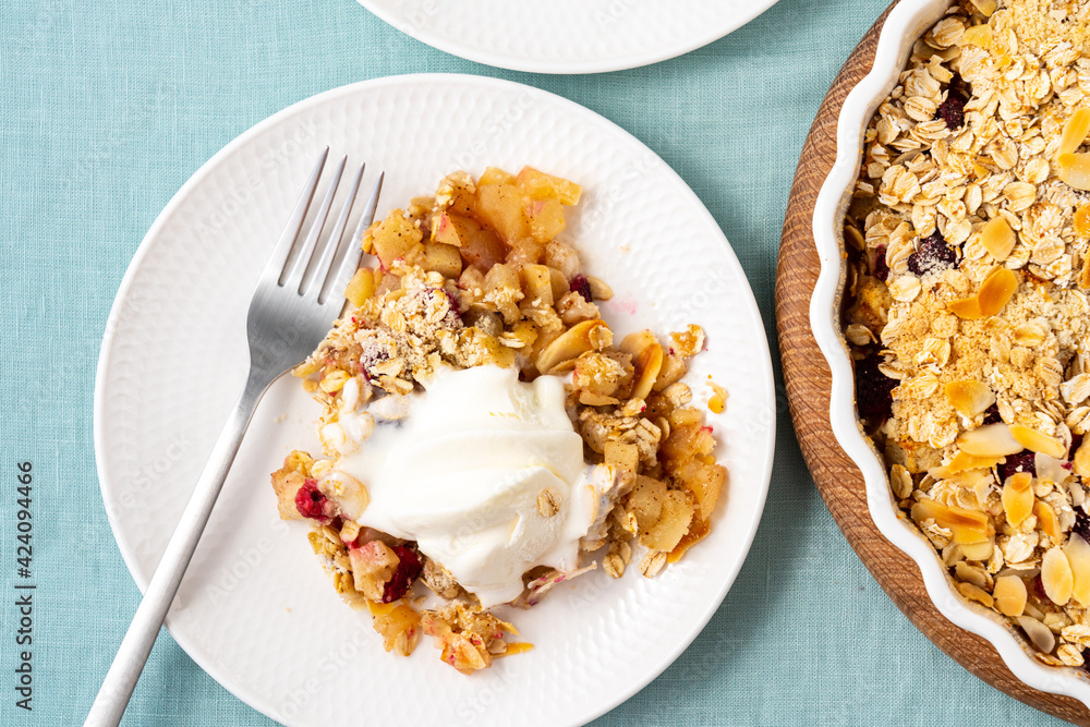 Close up apple pear crumble with ice cream, streusel. Healthy diet dessert stewed fruit topped crisp oats crumbly mixture with nuts. Apple cobbler gluten free pie in plate on tablecloth. Top view Close up apple pear crumble with ice cream, streusel. Healthy diet dessert stewed fruit topped crisp oats crumbly mixture with nuts. Apple cobbler gluten free pie in plate on tablecloth. Top view